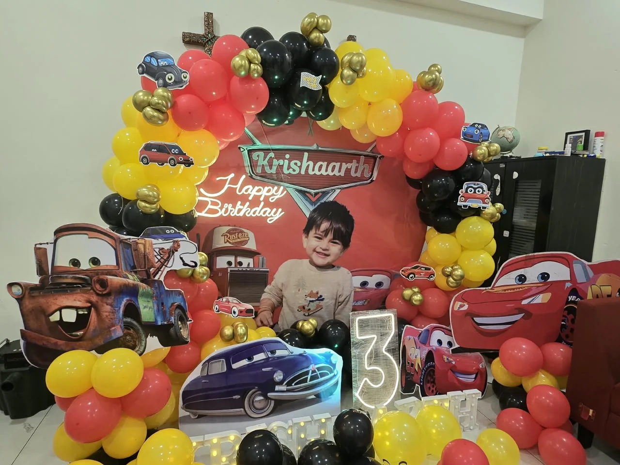 Cars-themed birthday with a red, yellow and black balloon ring around a portrait backdrop